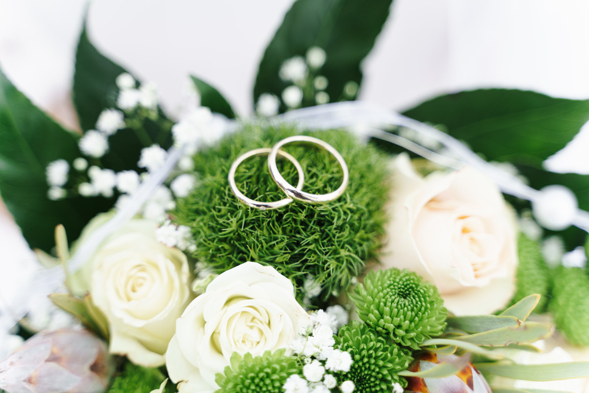Hochzeitsringe auf dem Brautstrauß mit weiße Rosen