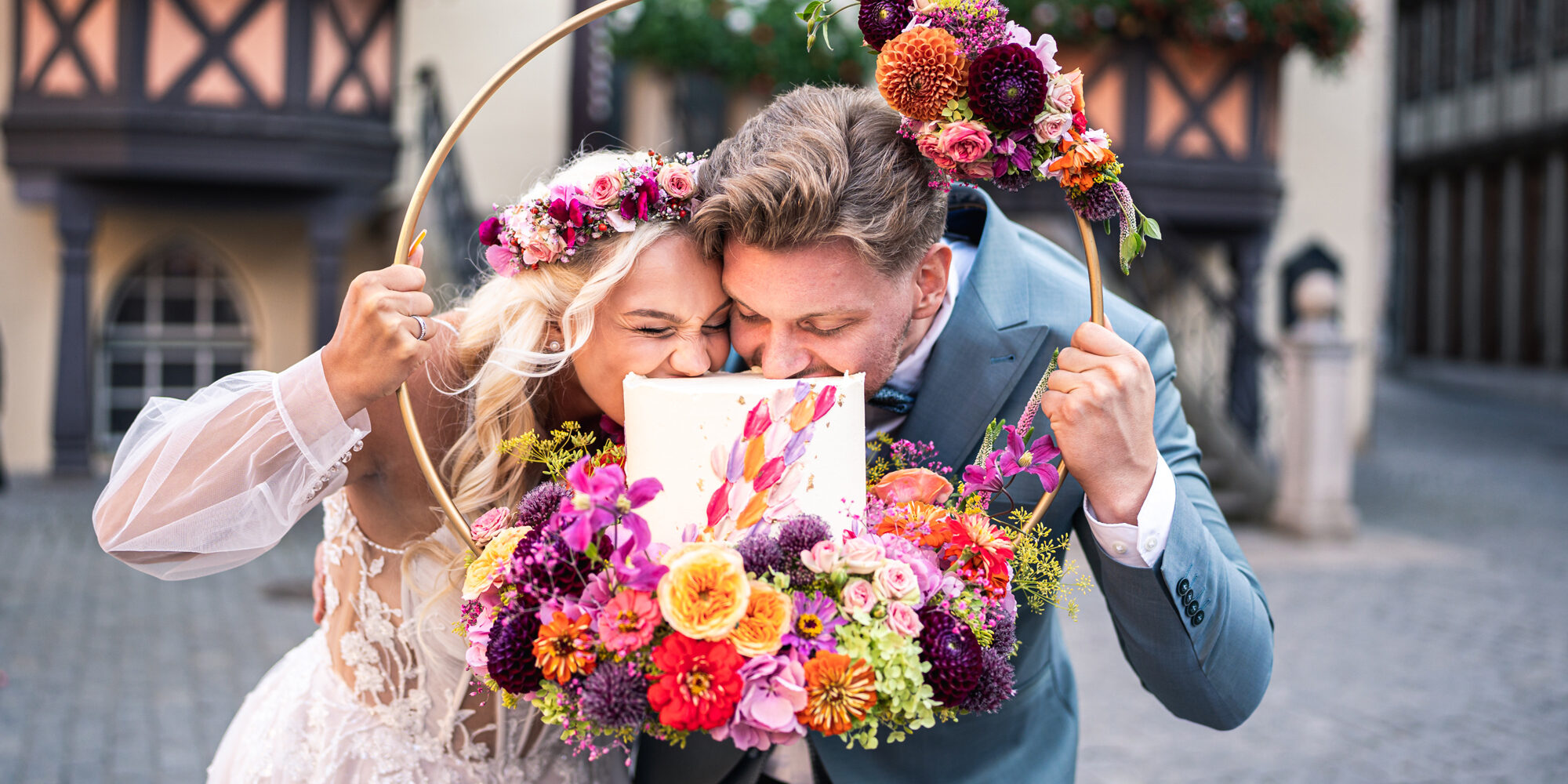 Hochzeitspaar beisst in ein Stück Kuchen vor dem Rathaus Wernigerode