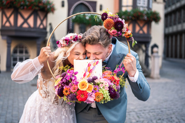 Hochzeitspaar beisst in ein Stück Kuchen vor dem Rathaus Wernigerode